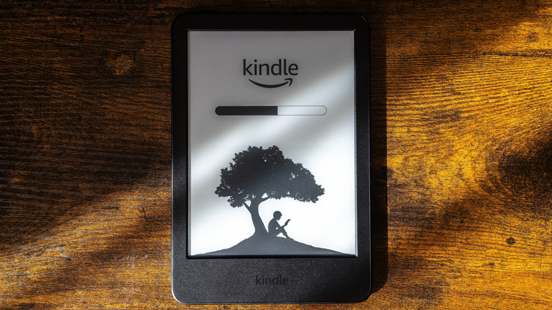 A Kindle device sitting on a wooden surface and displaying a loading screen