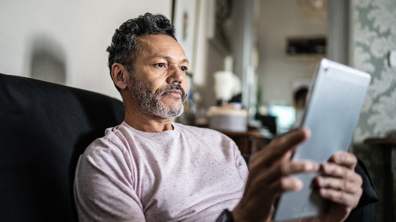 Man with a troubled expression while looking at an e-reader device