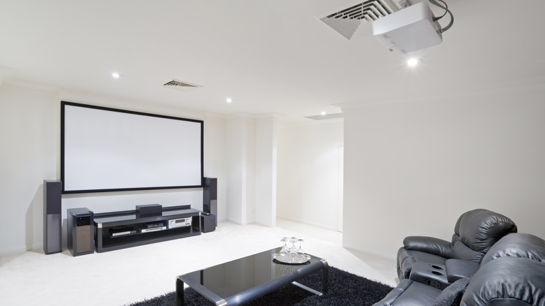A home theater with a large screen, projector, and overstuffed seats.