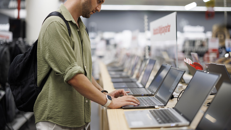 Man checking out laptops at a retail store display