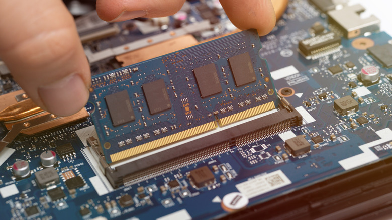 Person installing RAM on a laptop motherboard