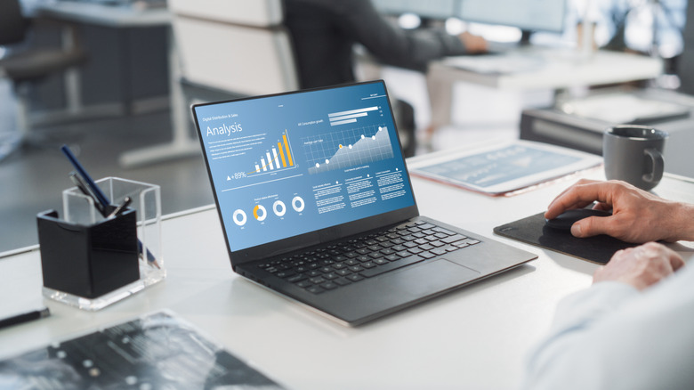 man using laptop on white desk in office setting