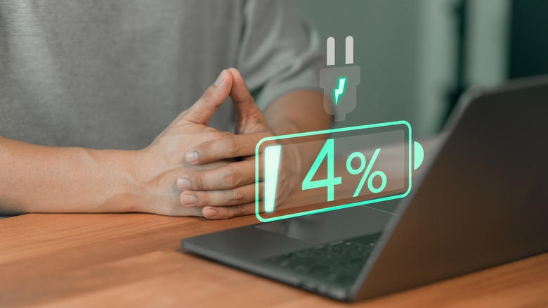 A laptop on a table with an illustration over it, showing four percent of battery.