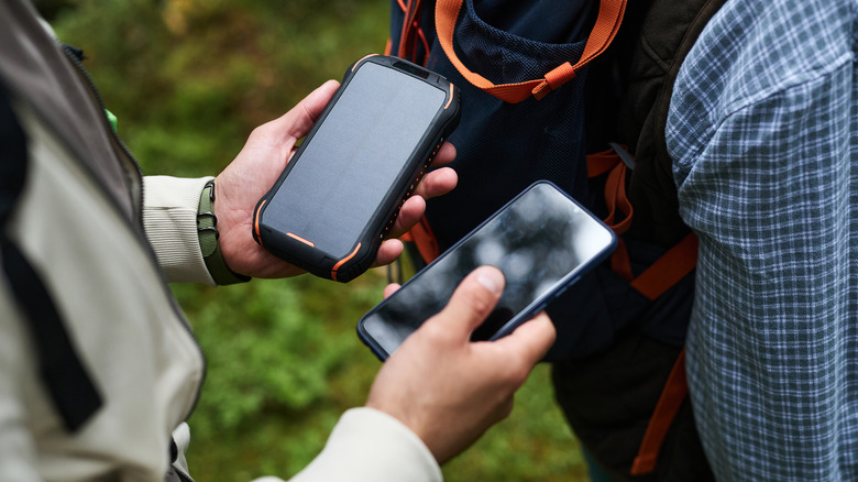 A person using a solar charger to power a cell phone while outdoors