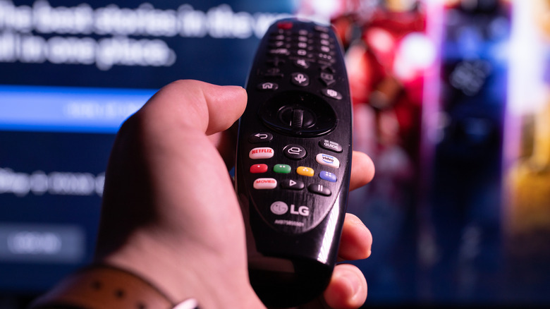 a hand holding an LG TV remote browsing channels