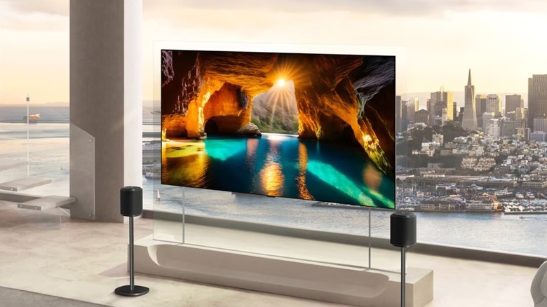 A promotional image for the 2026 OLED Wallpaper TV from LG, the TV is sitting against a large window that overlooks a large city