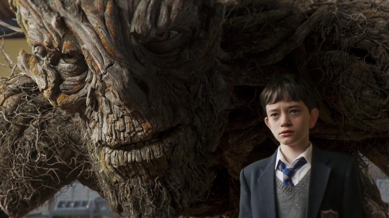 Conor O'Malley (Lewis MacDougall) with the Monster crouching behind him in A Monster Calls