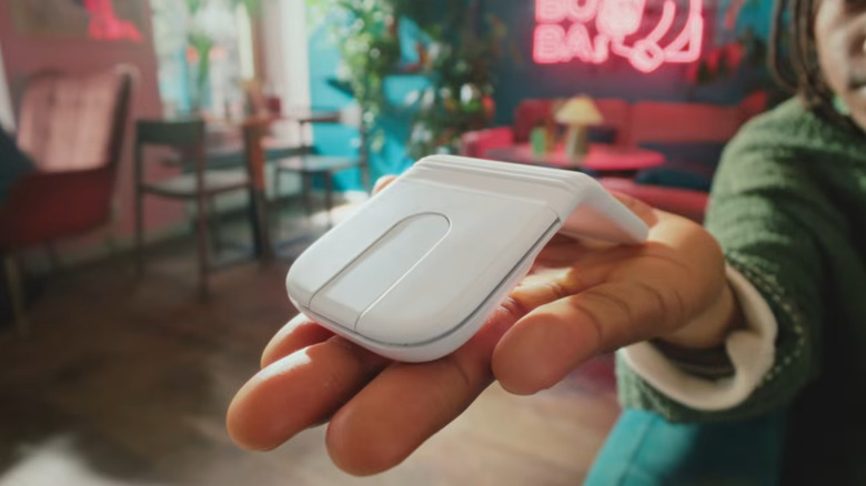 A person holding a white Logitech Mobi Fold mouse