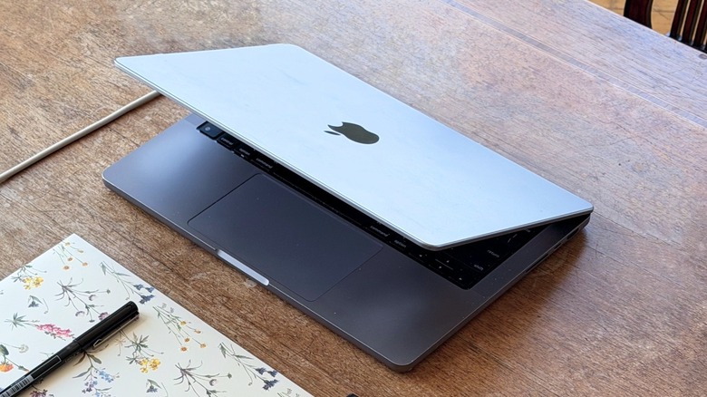 A half-closed MacBook Pro on a wooden table