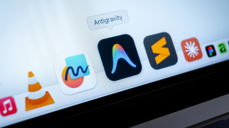 laptop screen displays the macOS Dock featuring Google Antigravity extension, and VLC media player.