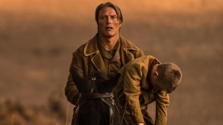 Mads Mikkelsen as Jon riding on a horse with a boy in The Salvation