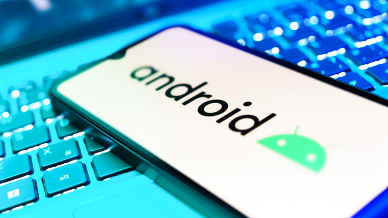 The Android logo on a smartphone resting on a keyboard with blue light