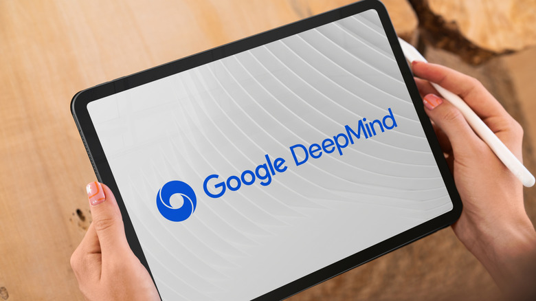 Hands holding a tablet with a stylus, displaying the Google DeepMind logo