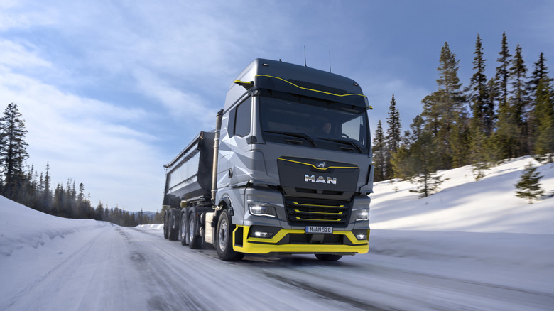 MAN's grey, yellow lined hydrogen truck drives through a wintery landscape.