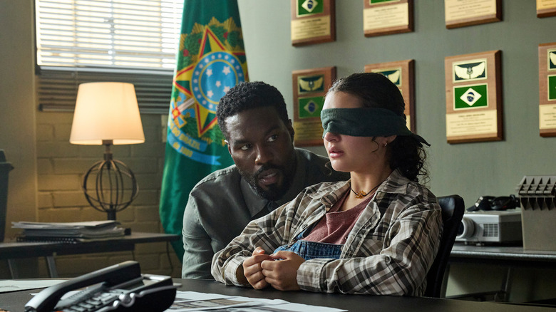 John Creasy talks to a blindfolded Poe in what looks like the Brazilian embassy.