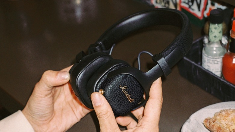 A person holding Marshall's new Milton A.N.C. headphones in a restaurant