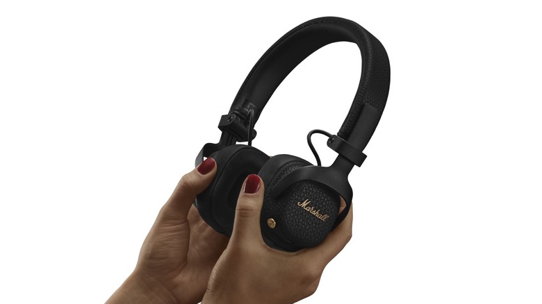 A person holding Marshall Milton A.N.C. headphones against a white background