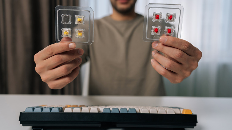 Person holding switches in front of compact mechanical keyboard