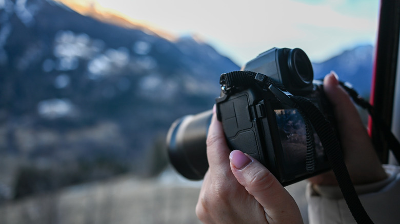 A woman capturing a mountain view with a DSLR