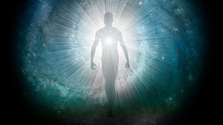 Silhouette of a figure emerging from a cosmic background with light behind.