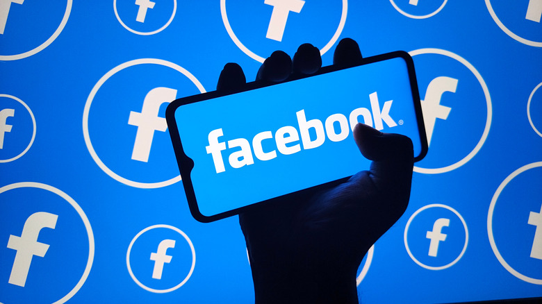 Facebook logo on a phone against a background with Facebook logos