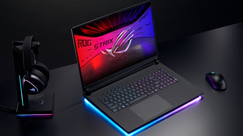 A photo of the ASUS ROG Strix Gaming Laptop next to a black mouse and black headphones sitting on their stand