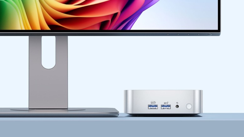 A photo of the Geekom A6 Mini PC next to a large display, most of the display is out of frame