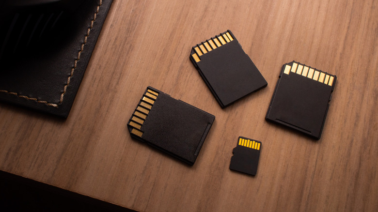 A microSD card laid next to three full-size SD card adapters.