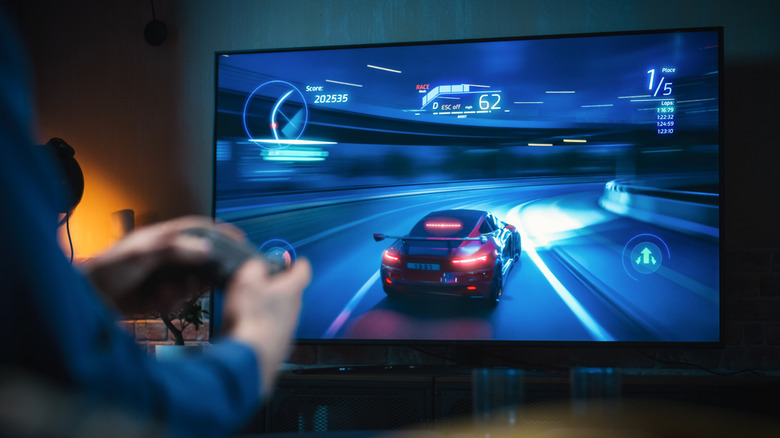 person playing racing video game on large screen tv