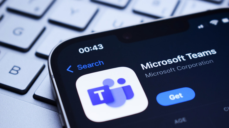 A Microsoft Teams application is displayed on a phone screen atop a keyboard