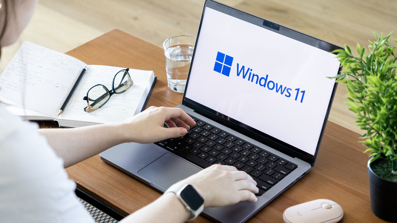 Person using a laptop showcasing the Windows 11 logo