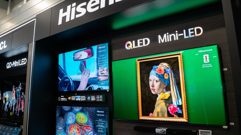 Hisense QLED Mini-LED TVs on display in an electronics store, showing colorful demo content and promotional branding.