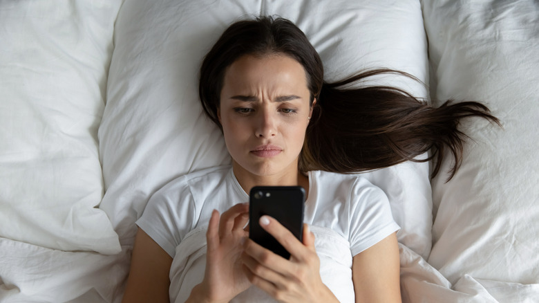 Young woman looking anxious while using her smartphone