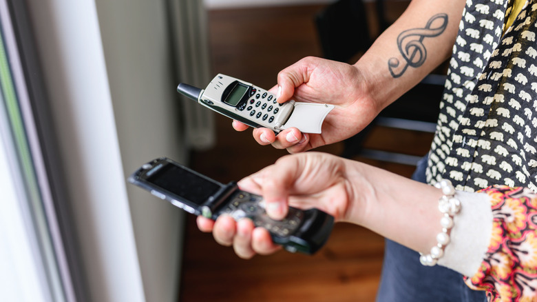 Hands of young people holding retro cell phones