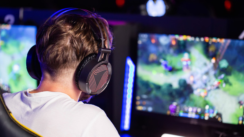 Person wearing gaming headset playing a PC game on a monitor.