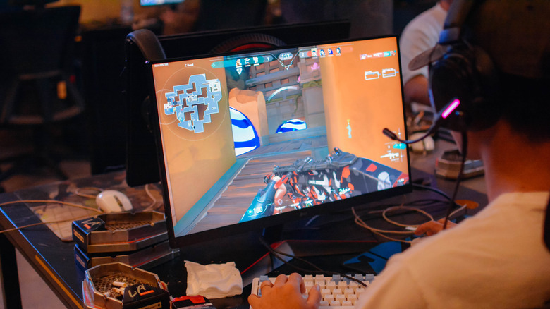 Player using keyboard and mouse playing Valorant on a PC monitor with headset.
