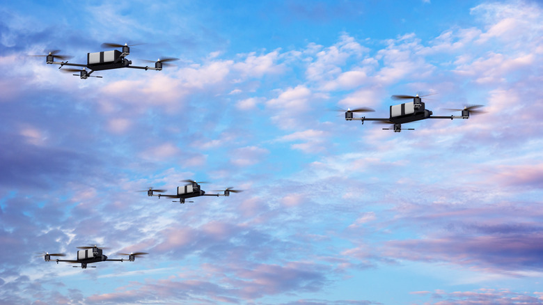 A fleet of drones flying against a cloudy sky