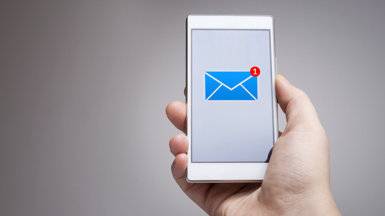 Hand holding a smartphone displaying an email icon with a notification badge indicating one new message.