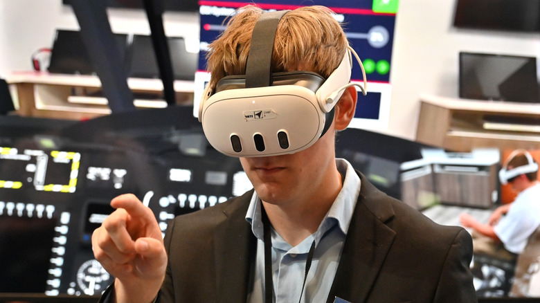 Person wearing a virtual reality headset and interacting with a simulated interface, with a tech or demo environment in the background.
