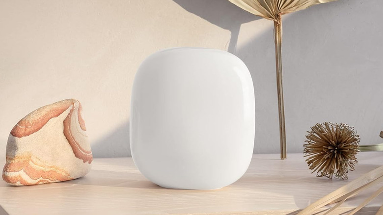 Google Nest Wifi Pro 6E router on a wooden table with decorative items.