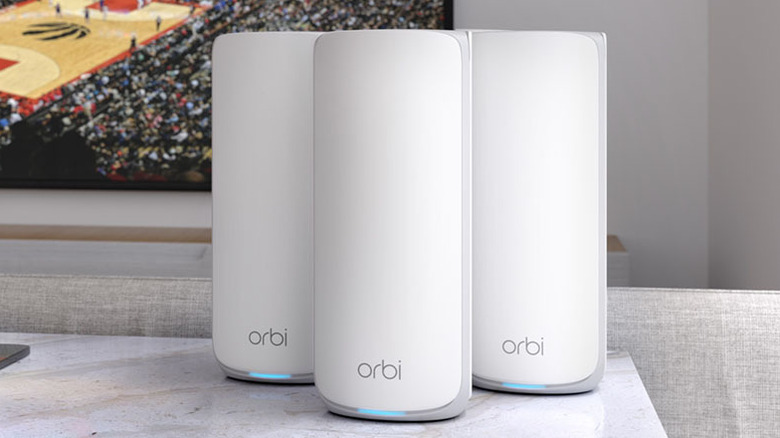 Netgear Orbi 870 Series mesh routers placed on a table in a living room.