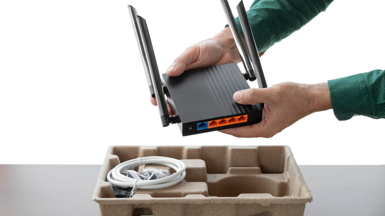Someone unpackaging a new Wi-Fi router fresh out of the box.