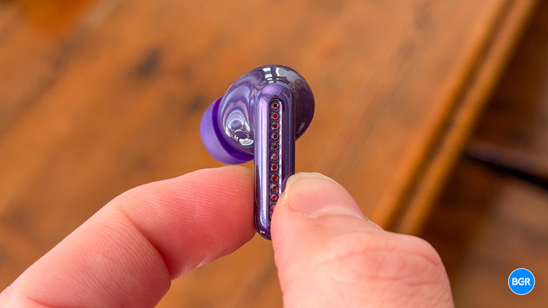 Holding a Motorola Moto Buds 2 Plus earbuds