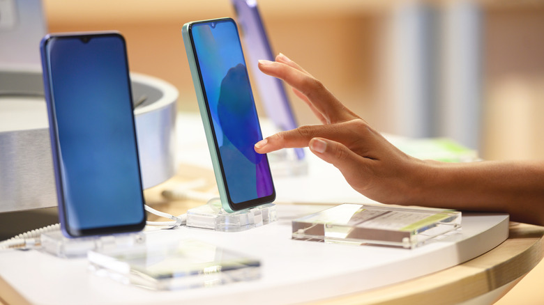 A person touching a phone's display in a retail store