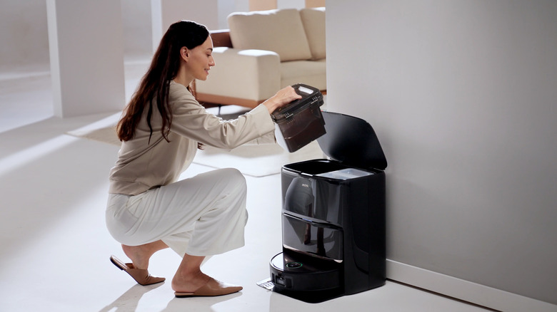 Woman lifting dirty tank from MOVA Z60 Ultra Roller Complete base station