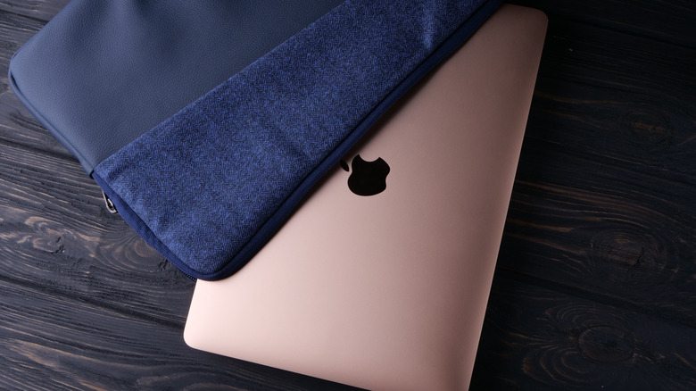 A rose gold Macbook partially tucked into a blue cloth cover