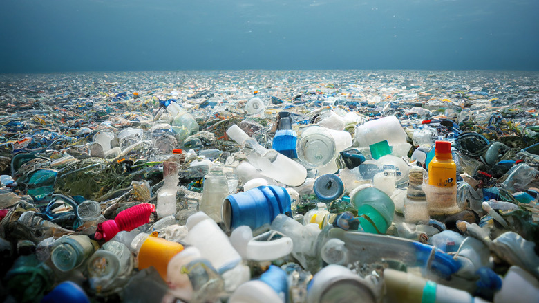 Plastic pollution in the ocean with bottles and waste visible.