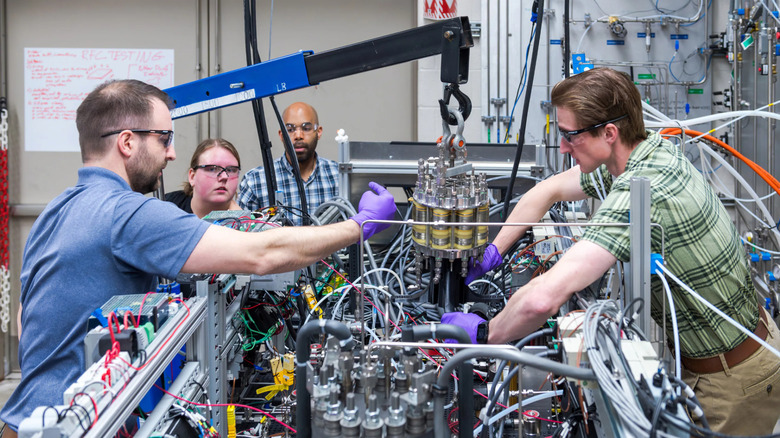 A group of four NASA engineers install a fuel cell onto the regenerative fuel cell system.