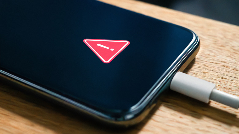 Phone with charger plugged in with red triangle warning on the screen
