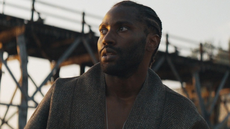 John David Washington as Joshua Taylor in front of a bridge in The Creator